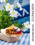 Small photo of Greek fast food delivery.Gyros sandwich with fried meat wrapped in paper. Gyro pita take away, street food pita bread wraps with meat, traditional greek food on wooden table