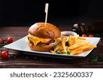 Cheeseburger with beef, tomato, pickles cucumber, red onion, lettuce, cheddar cheese, ketchup and French fries. Tasty burger cooking with beef, tomato, cheese, cucumber and lettuce.