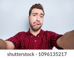 Small photo of Don't be shy! Close up portrait of excited sincere openhearted emancipated handsome guy fooling around on camera and taking selfie, isolated on gray background