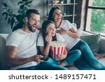 Portrait of nice attractive lovely positive glad cheerful cheery family wearing casual white t-shirts jeans denim sitting on sofa having fun watching funny video enjoying spending free time