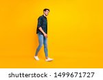 Full length body size photo of cheerful attractive guy walking towards sales wearing sneakers isolated over yellow vivid color background