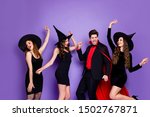 Small photo of Photo of witch ladies and warlock guy friendship chilling at halloween party dancing wear black dresses hats and vampire coat isolated purple color background