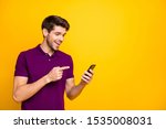 Portrait of his he nice attractive cheerful cheery glad guy wearing violet shirt holding in hands pointing at new gadget web service isolated on bright vivid shine vibrant yellow color background