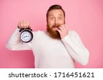 Small photo of Frustrated anxious guy hold clock see time shocked he miss work study deadline feel panic bite nails wear sweater isolated over pastel color background