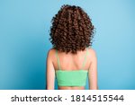 Rear back photo of young lady stand big extensive volume hairstyle nice curls sporty athletic trained spine back after exercises wear green crop top isolated blue color background