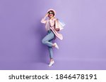 Full size photo of positive pretty girl jump hold purchases wear glasses coat jeans shoes isolated on purple background