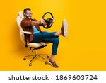 Small photo of Full length body photo of happy fooling man in chair keeping steering wheel pretending car driver isolated vivid yellow color background