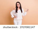 Photo of young attractive woman happy positive smile confident hold glasses isolated over beige color background