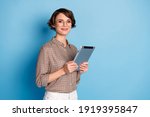 Small photo of Portrait of half turned nice person smile holding tablet wear checkered outfit isolated on blue color background