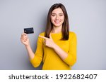 Portrait of lovely glad cheerful girl holding in hands demonstrating bank card solution isolated over grey color background