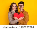 Small photo of Portrait of attractive cheerful careful amorous couple embracing holding heart shape form figure isolated on bright yellow color background