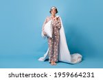 Full length photo of charming happy woman hold blanket pillow wear pajama barefoot isolated on pastel blue color background