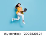 Small photo of Full body profile side photo of young woman happy positive smile jump up go run hold laptop isolated over blue color background