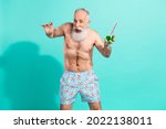 Portrait of attractive elderly cheery funky grey-haired man drinking mojito having fun isolated over bright teal turquoise color background