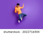 Small photo of Full length photo of young crazy dark skin man jump up air fists winner celebrate isolated on violet color background