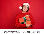 Photo portrait young woman keeping xmas gift in headwear looking copyspace isolated bright red color background