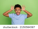 Small photo of Portrait of handsome cheerful foolish pre-teen boy teasing fooling grimacing isolated over green color background