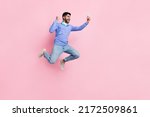 Small photo of Full length photo of funny lucky arabian man wear long sleeve shirt blogging gadget jumping running isolated pink color background