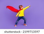 Small photo of Full length photo of funky cool small son wear red mantle wind blowing rising fist isolated violet color background