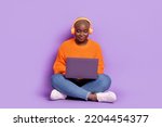 Full size portrait of charming nice girl sit floor listen music use netbook isolated on purple color background