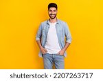 Small photo of Photo of young positive guy confidently looking camera sure best worker hands pockets isolated on yellow color background