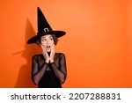 Small photo of Photo of cute young girl astonished touch cheeks look empty space dressed trendy black halloween witch outfit isolated on orange background