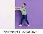 Full body photo of handsome young man pulling white empty space placard wear trendy gray look isolated on violet color background