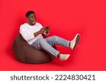 Small photo of Full body portrait of excited crazy person sitting bag play videogames isolated on red color background