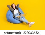 Full body photo brunette hair vietnamese entrepreneur it manager lying down pouf nap sleep with laptop after work isolated on yellow color background