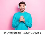 Photo of funny excited young man overjoyed shocked cheap itunes subscription hold phone listen headphones isolated on pink color background