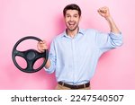 Photo of young excited positive happy winner lottery new sportcar raise fist up hold steering wheel enjoy his luck isolated on pink color background