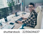 Small photo of Photo of happy cheerful coder dressed eyewear writing keyboard web designing indoors workplace workstation loft