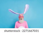 Small photo of Portrait of funky astonished positive elderly pensioner wear pink bunny costume impressed staring isolated on blue color background