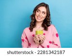 Portrait of young adorable cute lady brunette hair hold green cup of tea smiling enjoy aroma tea look empty space isolated on blue color background