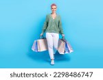Full body cadre of satisfied stylish wear model promoter beautiful woman with bags from new yorker store isolated on blue color background