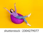 Small photo of Full length photo of careless girl chilling hands up relax time dormitory beanbag vacation weekend isolated on yellow color background