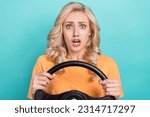 Portrait of confused scared person wear stylish t-shirt hold steering wheel astonished staring isolated on turquoise color background