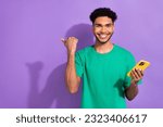 Small photo of Photo of funky positive guy dressed green t-shirt texting modern device thump empty space isolated violet color background