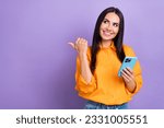 Photo of young lady blogger hold apple iphone direct finger looking empty space point finger itunes update isolated on purple background