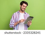 Small photo of Portrait of clever handsome person with bristle wear stylish clothes hold tablet scrolling social media isolated on green color background