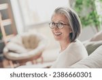 Photo of charming good mood elderly lady wear white cardigan spectacles smiling indoors apartment room