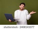 Small photo of Photo of uncertain unsure man wear trendy white clothes shrugging shoulders misunderstanding isolated on khaki color background