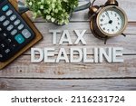 Tax Deadline alphabet letters with calculator and alarm clock on wooden background