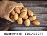 Raw potato food . Fresh potatoes in an old sack on wooden background. Top view