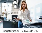 Young employee using modern printer in office