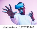 African american man in vr glasses, playing video games with virtual reality headset, trying to touch something with hand