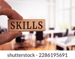 Small photo of Businessman shows a wooden block with the word skills. Business or job qualification, competence or leadership skills concept.