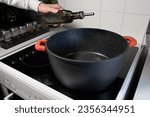Small photo of Stockpot - pouring vegetable oil into a pot on the stove for cooking