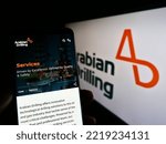 Small photo of Stuttgart, Germany - 10-18-2022: Person holding cellphone with webpage of Saudi business Arabian Drilling Company (ADC) on screen with logo. Focus on center of phone display. Unmodified photo.