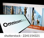 Small photo of Stuttgart, Germany - 12-10-2022: Smartphone with logo of American media company Omnicom Group Inc. on screen in front of business website. Focus on center-left of phone display. Unmodified photo.